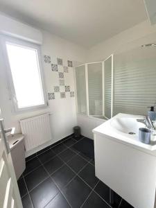 ein weißes Badezimmer mit Waschbecken und Fenster in der Unterkunft Maison cosy à Vaires sur Marne in Vaires-sur-Marne