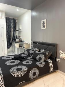a bedroom with a bed with a black and white comforter at Suite Zen Jacuzzi TV Integrée Clim Wifi Béziers Centre Arrivée Autonome 24h24 in Béziers