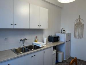 LikoporiáにあるDimos Apartmentsの白いキャビネット、シンク、冷蔵庫付きのキッチンが備わります。