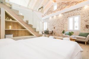 a bedroom with a white bed and a brick wall at Murofinto Homes De Vecchio in Corfu