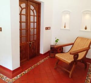 a room with a chair and a wooden door at Marari Beach Bungalow Resort Alleppey in Mararikulam