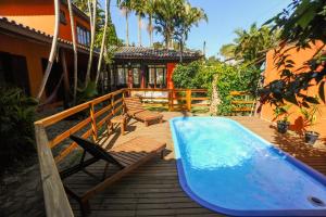 a swimming pool with a surfboard next to a house at Pousada Paradise Ferrugem in Garopaba