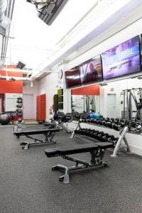 a gym with several tread machines and a large screen at Southern Exposure at The Brent Lofts in Pensacola