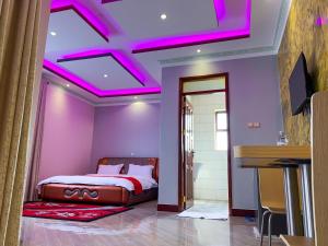 a bedroom with a purple ceiling with pink lighting at Das Berliner Hotel in Bulenga