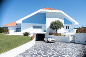 una casa blanca con un coche aparcado en la entrada en Best Beach Front Villa with Heated Pool - Sea La Vie, en Fão