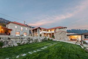 a large house with a stone wall and a yard at Casa da Ventozella in Penafiel