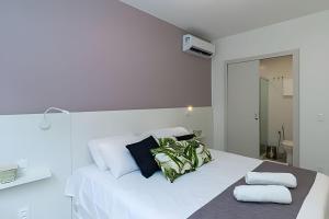 a white bedroom with a white bed with black pillows at Apto Copacabana 200 da Praia - Suíte + Lava&Seca in Rio de Janeiro
