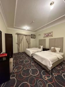 a hotel room with two beds and a carpet at اجنحة ارتياد للشقق المخدومه in Abha +4 photos