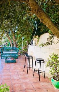a patio with two chairs and a bench and trees at Casa Jardín SevillaMia in Orihuela Costa in Orihuela Costa