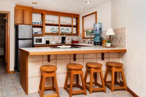 a kitchen with wooden stools at a kitchen counter at White Sands Cove E01-Partial Ocean View 2 BR by Stay Floreo in San Pedro