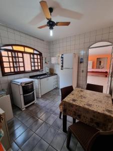 a kitchen with a table and a white refrigerator at Casa com piscina in Bertioga