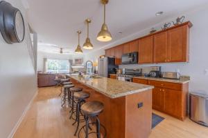 a kitchen with wooden cabinets and a counter with bar stools at Butler Street Condo #16 - Walking Distance to downtown Saugatuck - Newer vacation rental in Saugatuck
