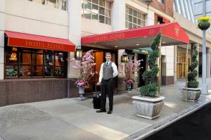 Hotel Elysee by Library Hotel Collection في نيويورك: رجل في بدلة يقف أمام مبنى