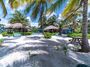 a beach with palm trees and a picnic table at White Sands Cove G04- Partial Ocean View 1 BR by Stay Floreo in San Pedro