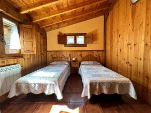 due letti in una stanza con pareti in legno di Las Casucas a Villegar
