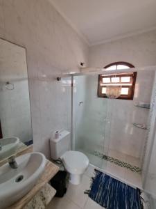 a bathroom with a toilet and a sink and a shower at Casa com piscina in Bertioga