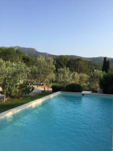 a large blue swimming pool with a mountain in the background at Domaine entier au havre de paix 4 chambres in Vauvenargues