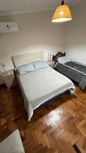 a bedroom with two beds and a lamp and wooden floors at Reconquista TEMPORARIO centro in Reconquista +7 photos