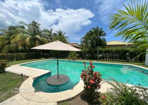 a swimming pool with an umbrella and a table with at Las Veraneras Villa - Pet Friendly in Acajutla