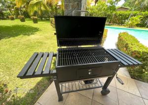 a grill sitting on a picnic table next to a pool at Las Veraneras Villa - Pet Friendly in Acajutla