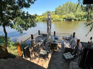 a patio with chairs and an umbrella next to a river at Bear Secret House in Ćuprija