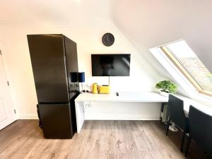 a black refrigerator in a room with a white desk at Stunning Modern, Private Apartment,15 Mins To Central London in The Hyde