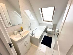 a white bathroom with a sink and a bath tub at Stunning Modern, Private Apartment,15 Mins To Central London in The Hyde