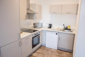Una cocina blanca con gabinetes blancos y un fregadero. en Highpoint, en Bradford