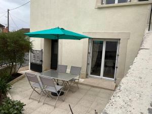 a table and chairs with an umbrella on a patio at Gîte - Comme à la maison in Saint-Martin-la-Rivière