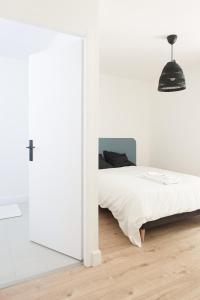 a white bedroom with a bed and a mirror at Appartement de l'UNESCO de Blaye- Spacieux & confort - 2 chambres in Blaye