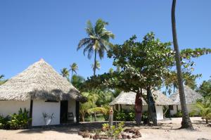 a couple of huts on the beach with palm trees at Pousada Entre as Águas in Imbassai
