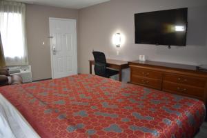 een hotelkamer met een bed, een bureau en een flatscreen-tv bij The Heritage Inn, Inc in Huntingdon +10 foto's