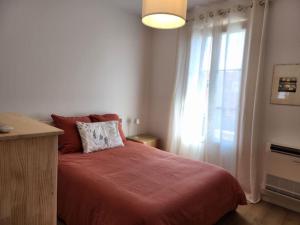 una camera da letto con un letto con una coperta rossa e una finestra di Nice Fac St Jean D'Angely a Nizza