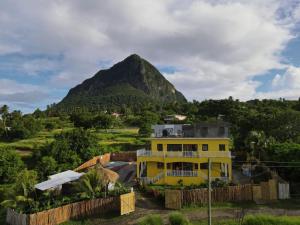 a yellow house with a mountain in the background at Desired View in Choiseul