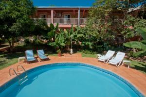 une piscine avec des chaises et une maison en arrière-plan dans l'établissement Hotel Posada La Sorgente, à Puerto Iguazú