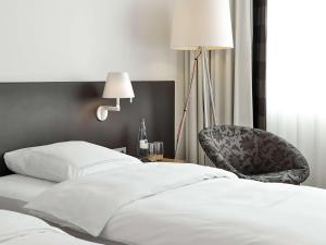 una camera da letto con un letto bianco e una sedia di Dorint Hotel Bremen a Brema