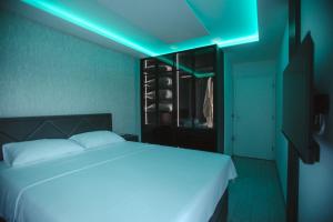 a bedroom with a white bed with a blue light at Lux Apartmani Teslić in Teslić