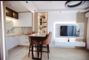 a kitchen with a table and chairs and a television at Lux Apartmani Teslić in Teslić +17 photos