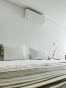 a white bedroom with a bed with white pillows at Apartamento Nuevo en el mejor club house de Neiva, a 5 minutos del aeropuerto y centro comercial in Neiva