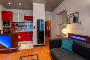 a living room with a couch and a kitchen with red cabinets at Cocon atypique en rive droite in Brest +16 photos