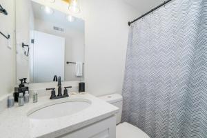 a bathroom with a sink and a shower curtain at Sojourn's Harborage Pelican Suite in North Camellia Acres +3 photos