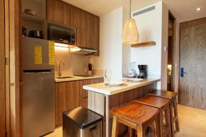 eine Küche mit einer Theke mit 2 Stühlen und einem Kühlschrank in der Unterkunft Hermoso Estudio frente al mar, Zantamar 306 in La Cruz de Huanacaxtle