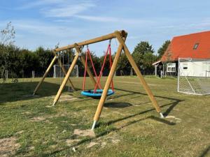 Un parque infantil con columpios en un campo en House in Scherpenisse near Oosterschelde, en Scherpenisse