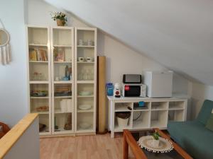 a living room with a white book shelf with a microwave at Habitación Anjana in Renedo de Piélagos