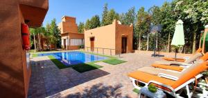 a swimming pool with lounge chairs and a house at Villa de luxe à marrakech in Marrakech