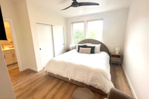 Un dormitorio con una cama blanca con ventilador de techo. en Bay View Loft, en Lincoln City