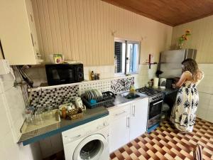 a woman standing in a kitchen with a washing machine at El Atardecer del Norte in Salão