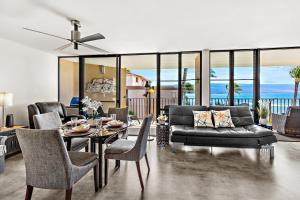 Una sala de estar con un sofá, una mesa y sillas. en Milowai 401, en Wailuku