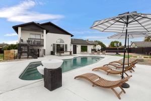 a swimming pool with two chairs and an umbrella at Lux Fun Zone Home - Sleeps 16 in Mesa