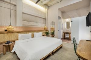 a bedroom with a large white bed and a table at Botánica Casa Hotel Manila by HOUSY HOST in Medellín